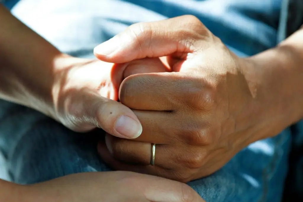 Two people holding hands for comfort and support