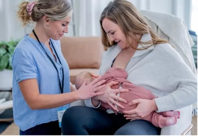 Nurse helping a woman feed a baby