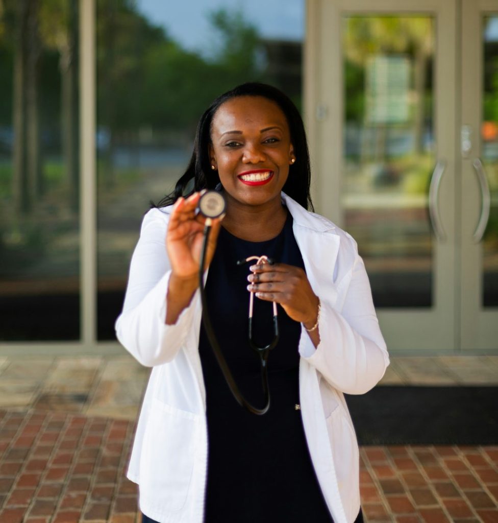 A doctor smiling holding up a stethoscope