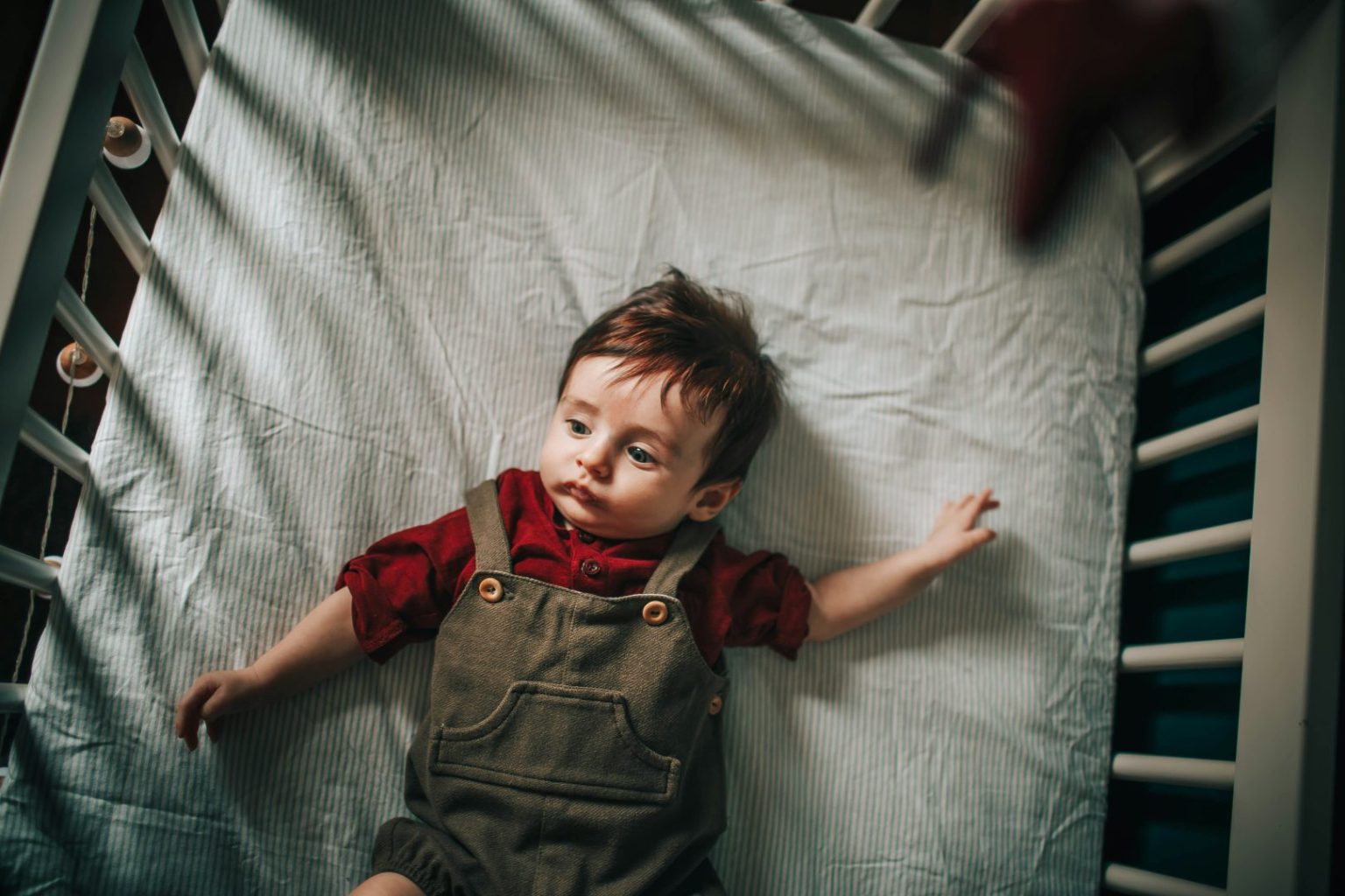 Toddler laying on his back in a crib
