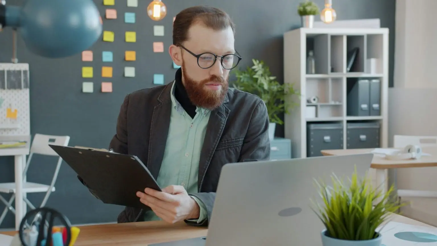 A man taking notes with a clipboard and a computer